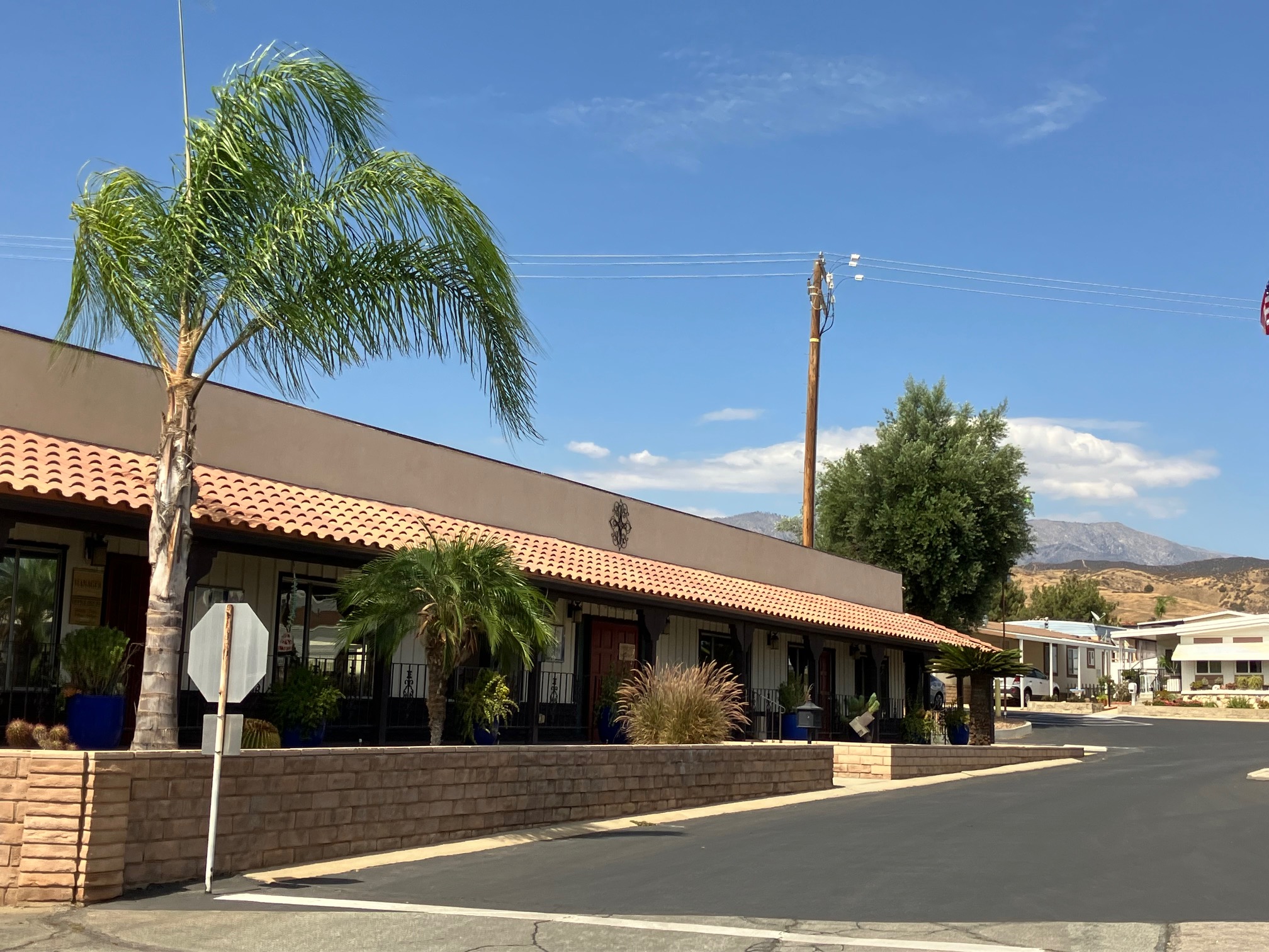 The Rancho Calimesa clubhouse, with a tiled roof, palms, and the mountains behind it